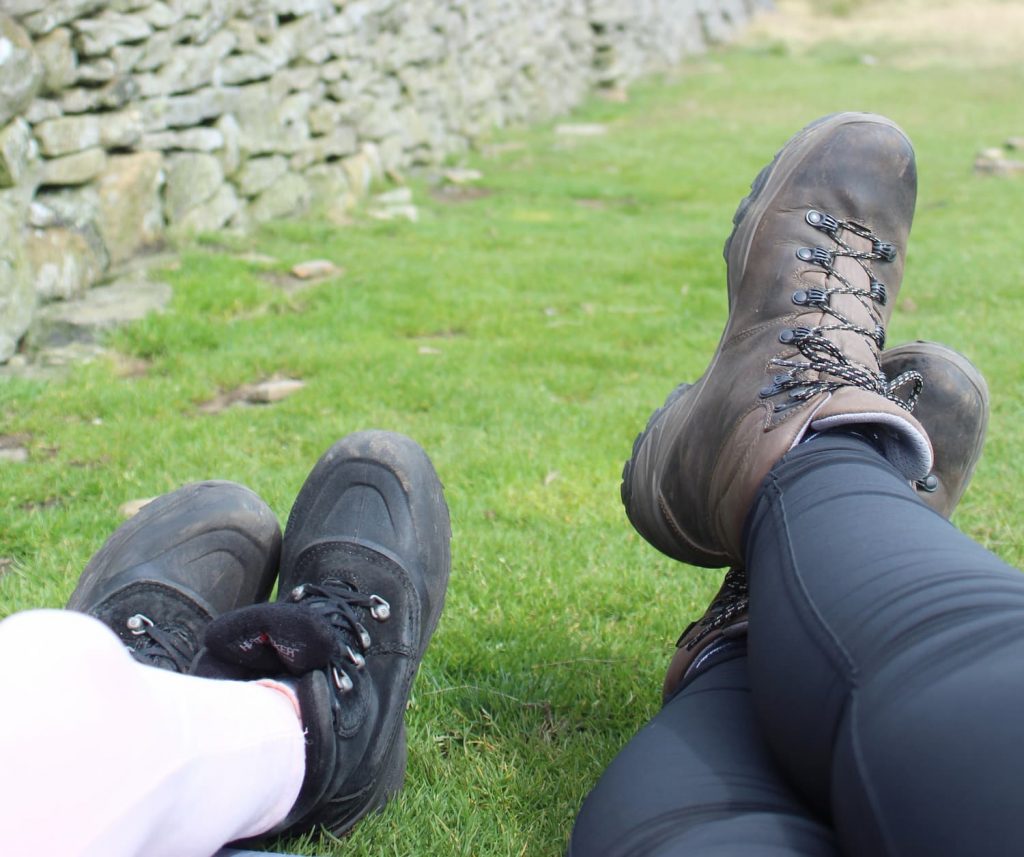 Two pairs of feet in walking boots at the summit of Pen-y-Ghent