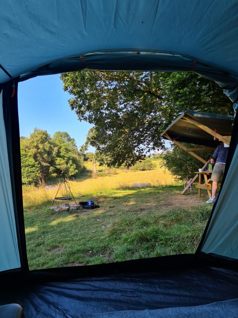 The view from the door of the tent into the hay meadow, with the camp fire and shelter. 