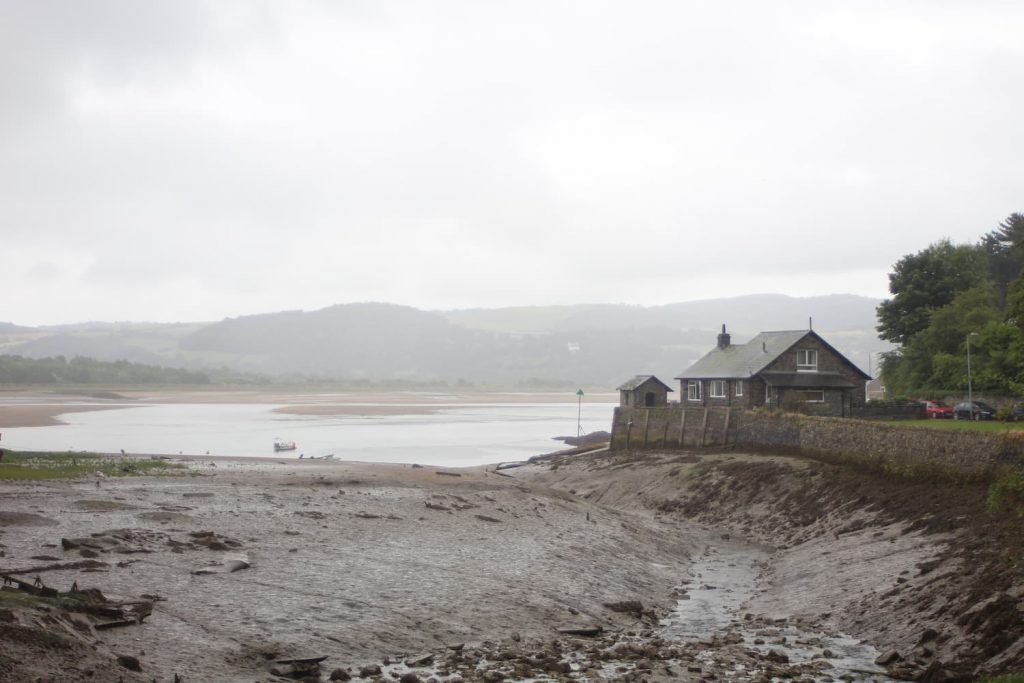 A moody Conwy beach with a small building in the foreground. 