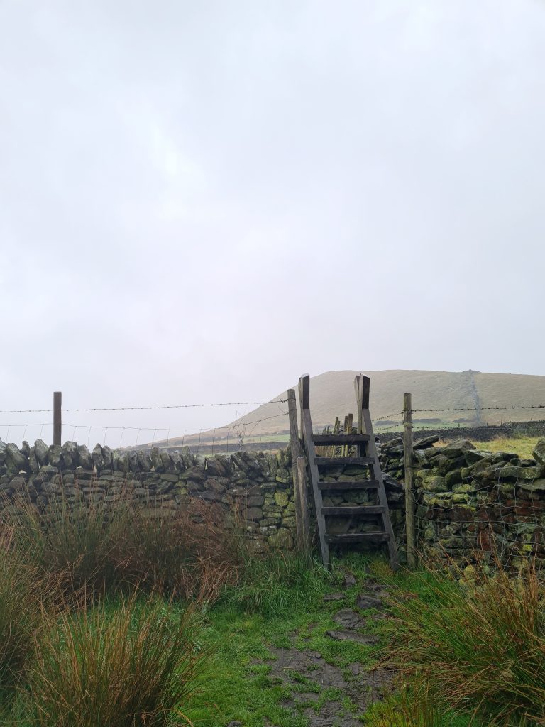 Wooden stile with Mount Famine in the background - The Wandering Wildflower Peak District Walks