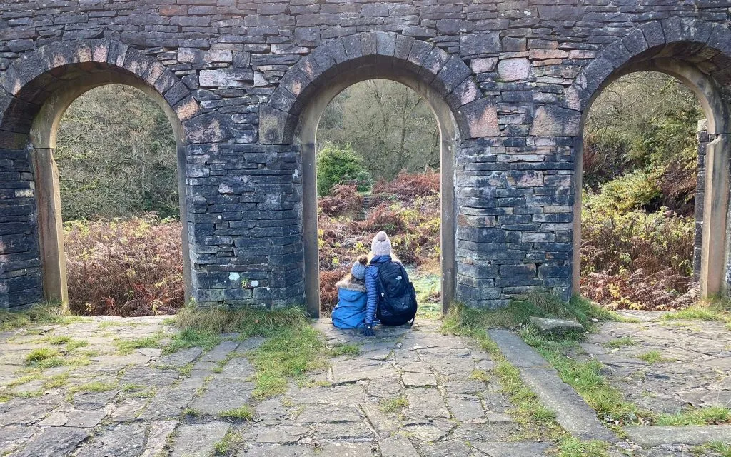 Mother and daughter sitting looking out of the windows in the ruins of Errwood Hall