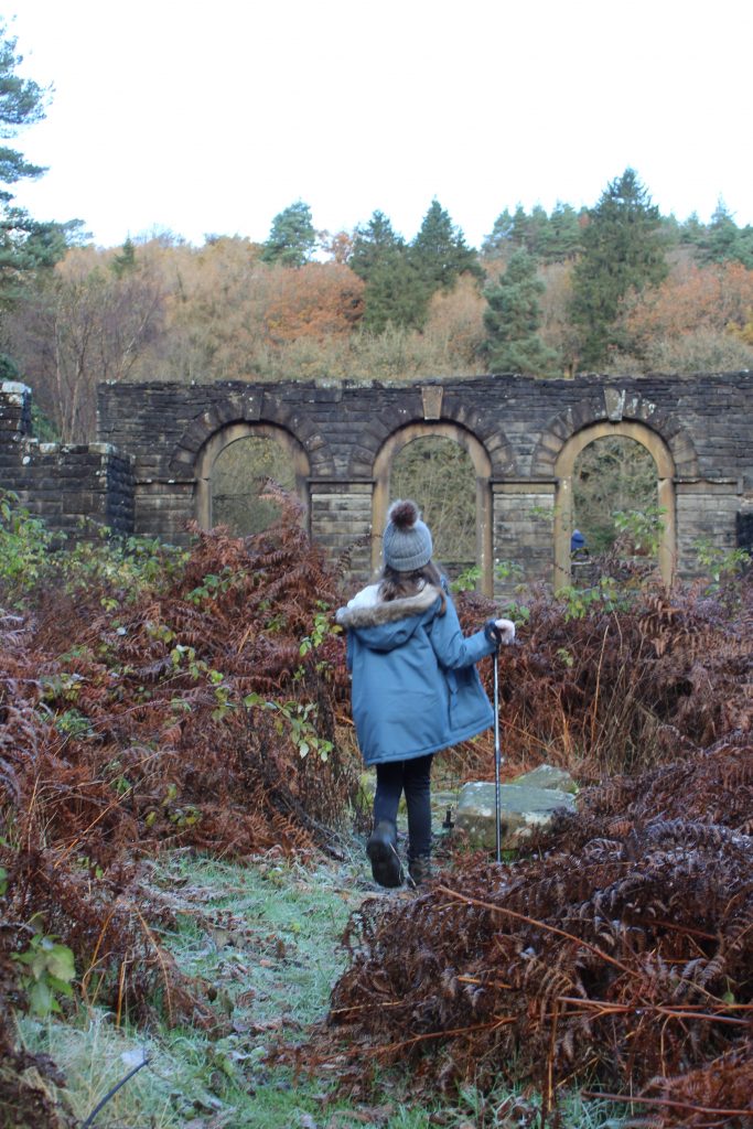 Small girl in a blue coat exploring the remains of Errwood Hall in Buxton