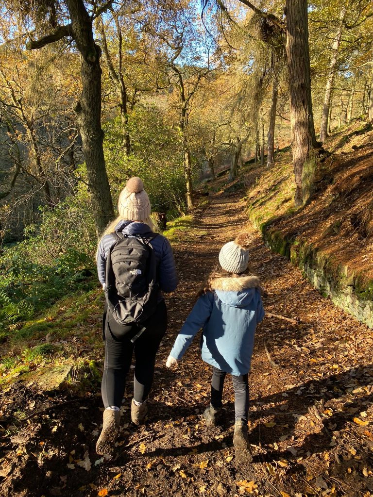 A woman and her daughter walking through woodland near Errwood Hall, The Peak District - a post on Hiking with Kids from The Wandering Wildflower