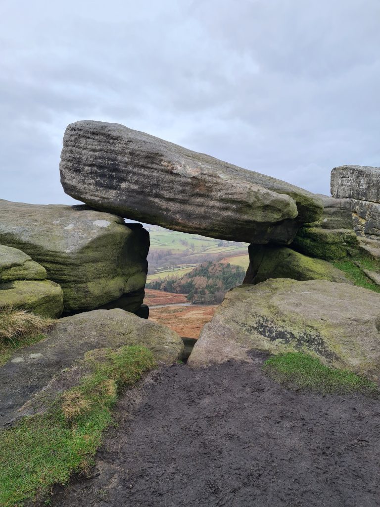 Rock formations on Stanage Edge forming a window frame to the views of the Peak District beyond