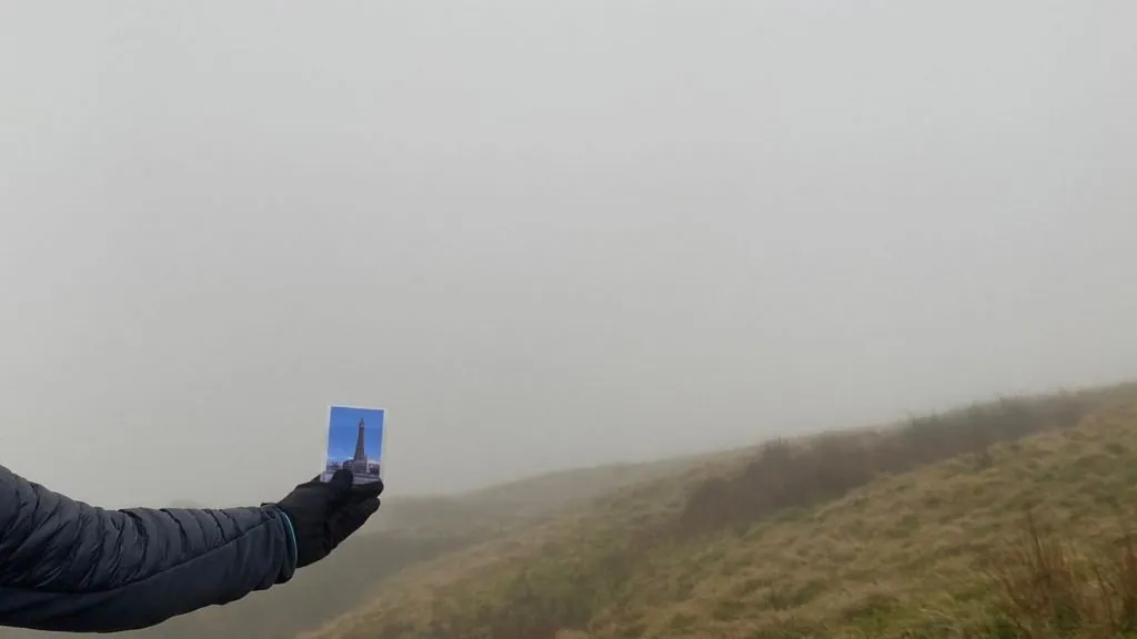 A hand holding a small picture of Blackpool Tower with a misty backdrop