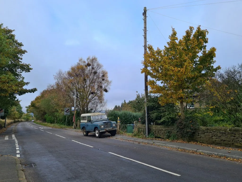 Vintage blue Land Rover Defender parked by the side of the road