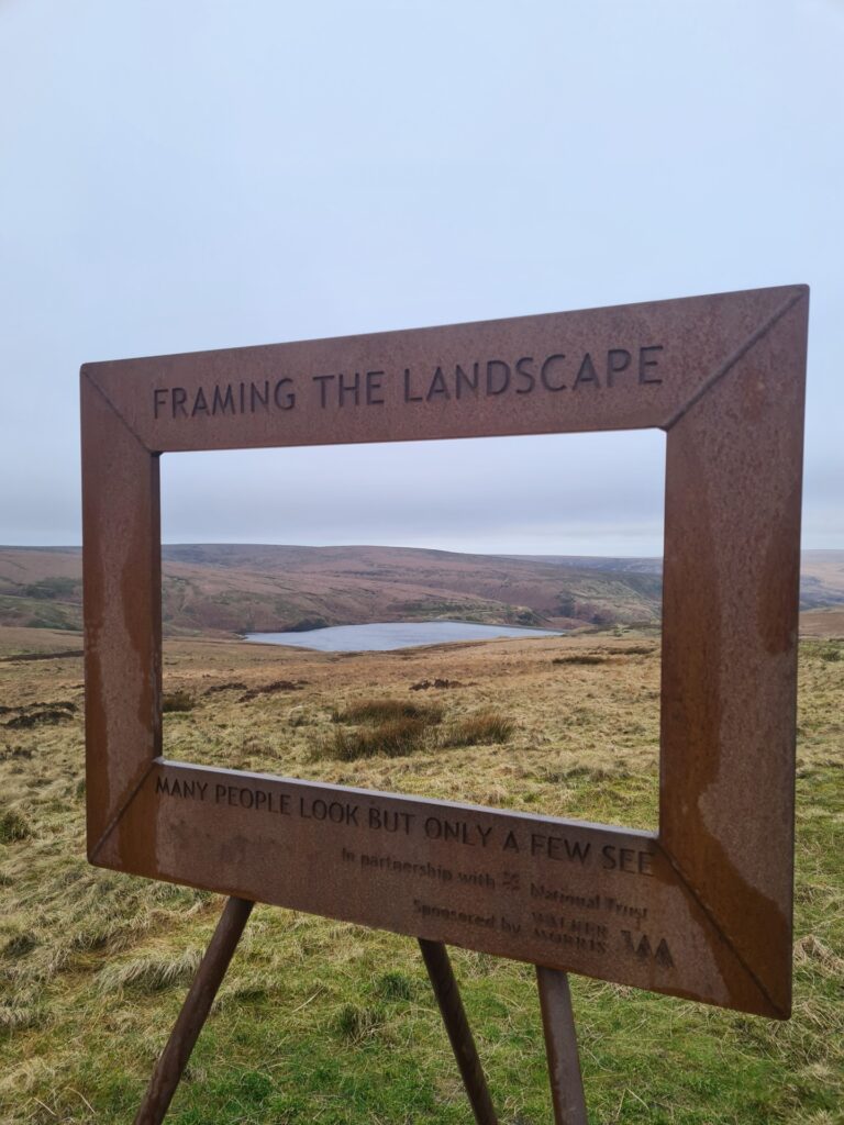 A metal picture frame showing the landscape behind and the words "Many people look but only a few see" in the Wessenden Valley