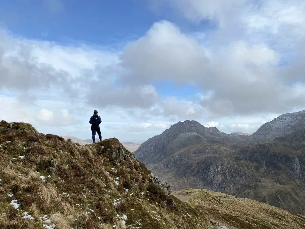 A woman stands looking over at Tryfan, the mountain
