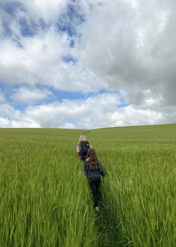 A woman and her daughter following a footpath through a barley field