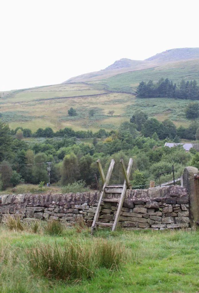 Wooden stile over a stone wall with views over moorland