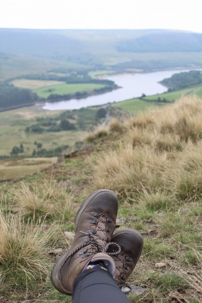 Pair of brown walking boots with views over Torside in the background