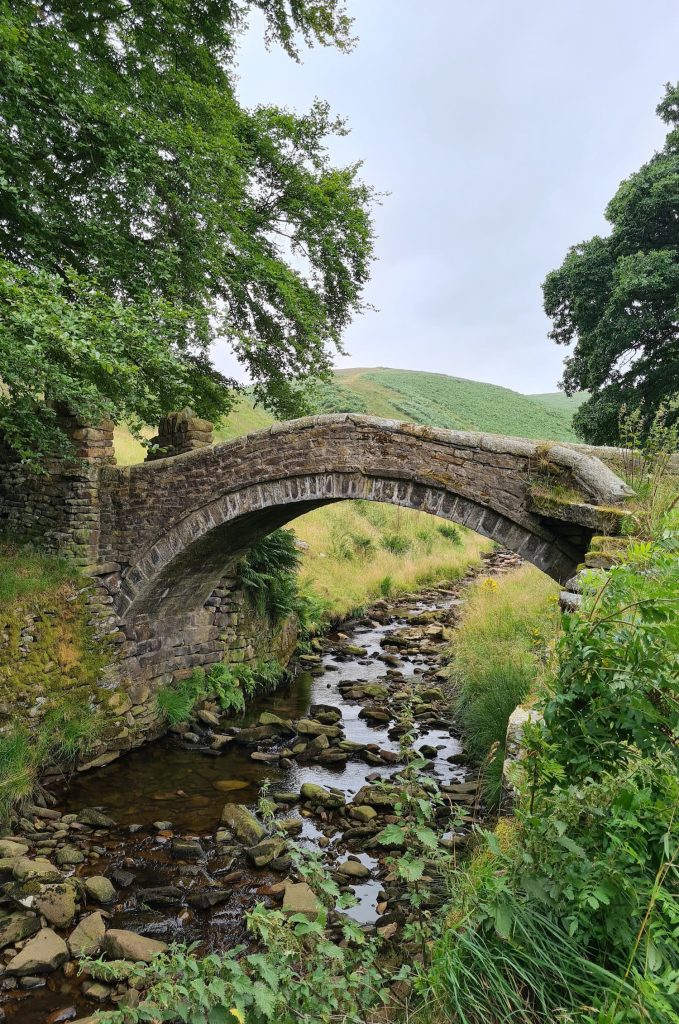 A beautiful old stone packhorse bridge over a stream - Eastergate Bridge in Marsden, West Yorkshire