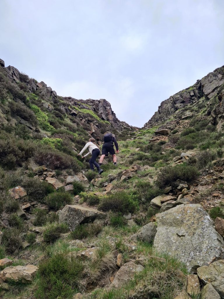 A father and daughter climbing up some large boulders - Dowstone Clough, Peak District scrambles