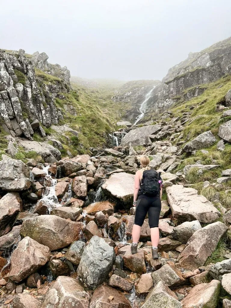 A woman looking up at Red Burn - Ben Nevis Route from The Wandering Wildflower