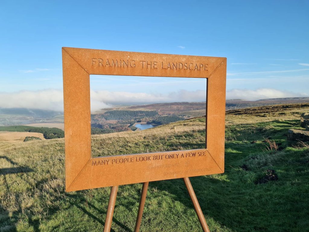 A metal picture frame surrounding a countryside view