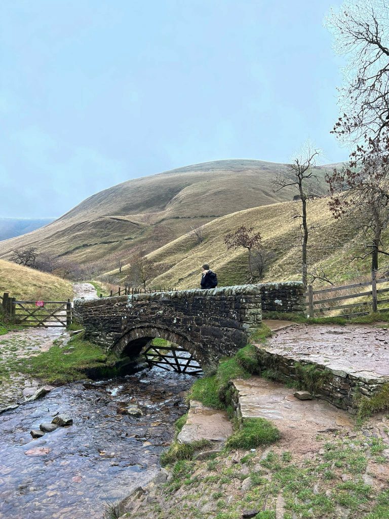 A woman walking over an old packhorse bridge on Jacob's Ladder