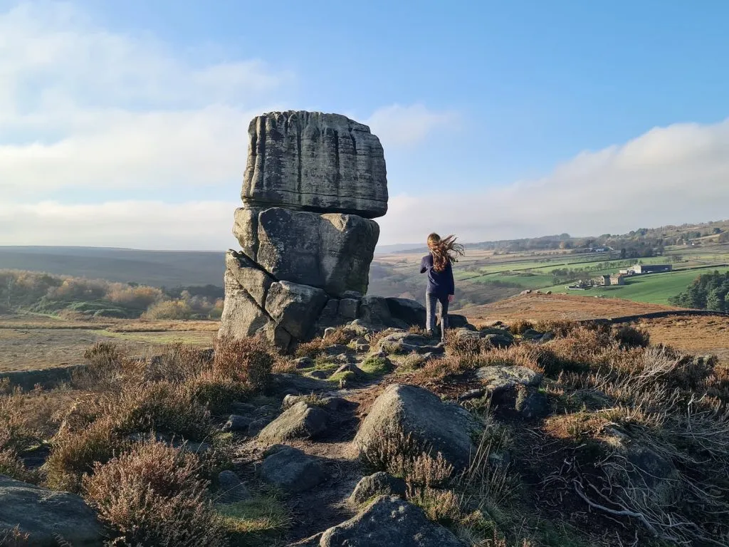 A young girl next to The Head Stone, a large gritstone formation on the Hallam Moors