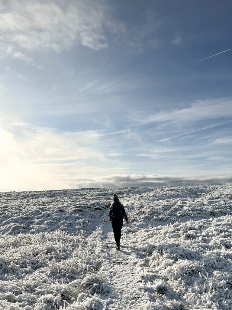 A woman walking on a snow covered moorland Black Hill