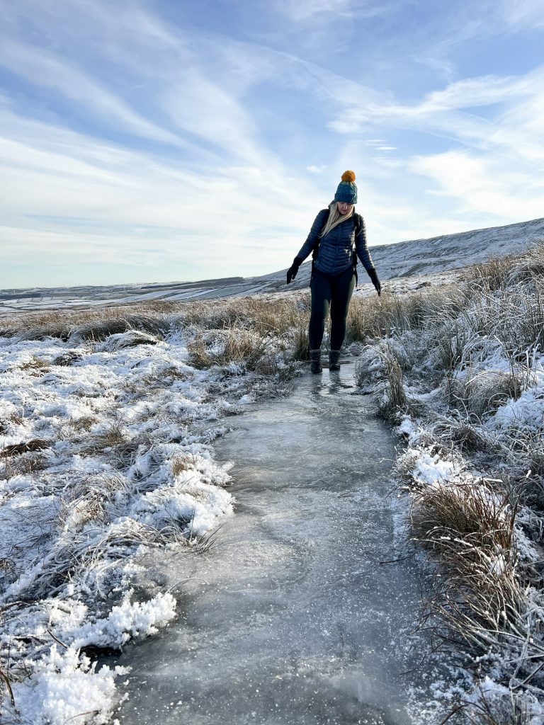 A woman treading carefully on an icy moorland path