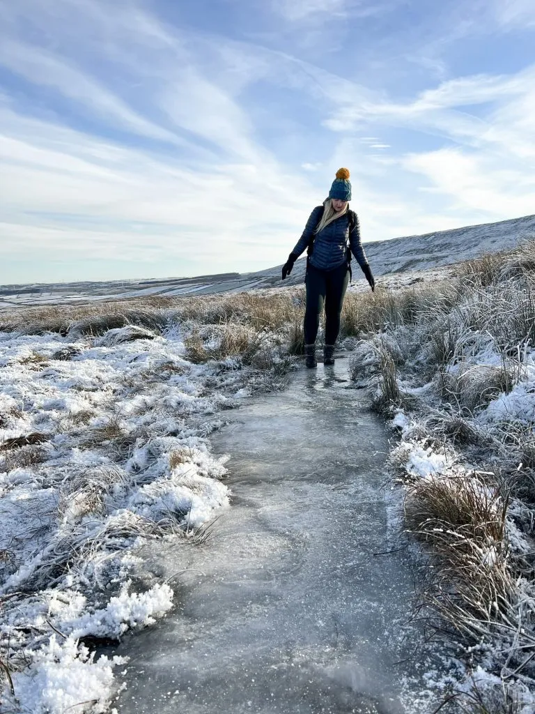 A woman treading carefully on an icy moorland path