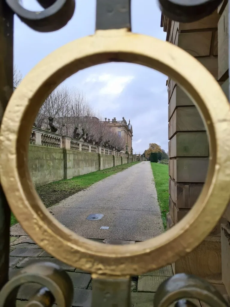 A view of Chatsworth House through a gold circle in the gate