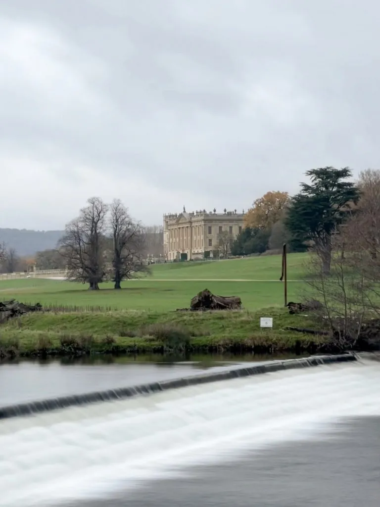 A view of Chatsworth House with a weir on the River Derwent