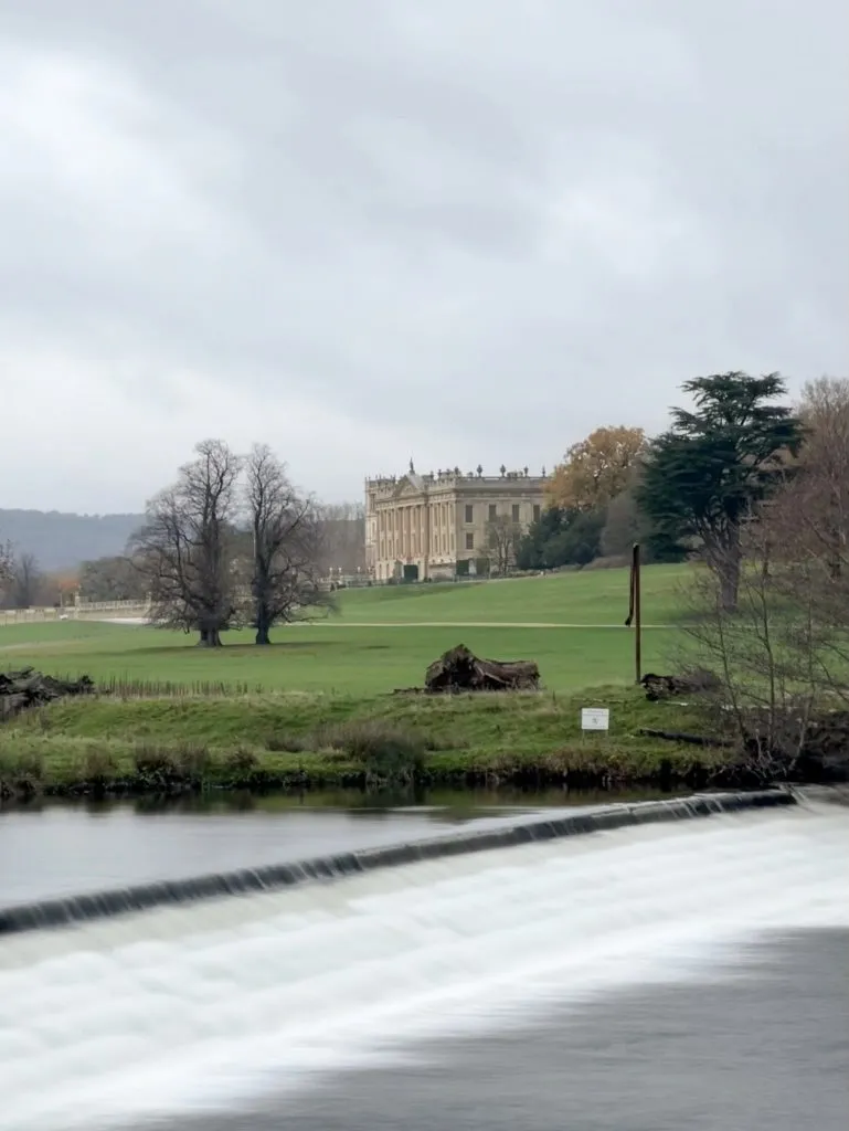 A view of Chatsworth House with a weir on the River Derwent