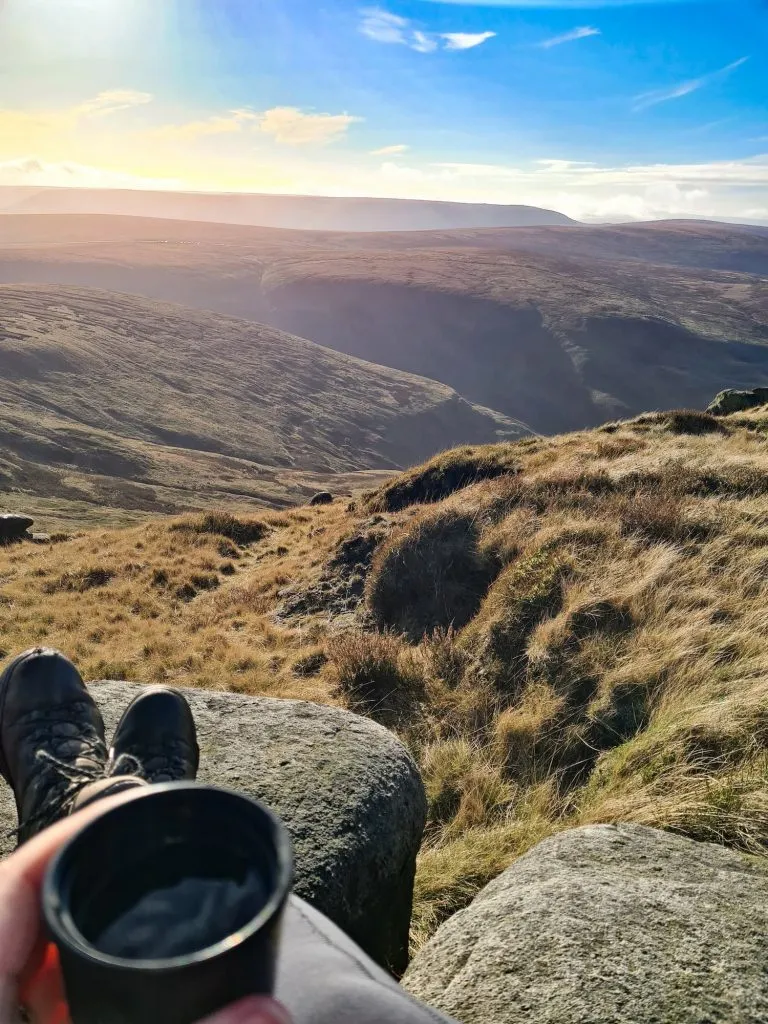 A cup of tea in the foreground with a view over the moors above Glossop