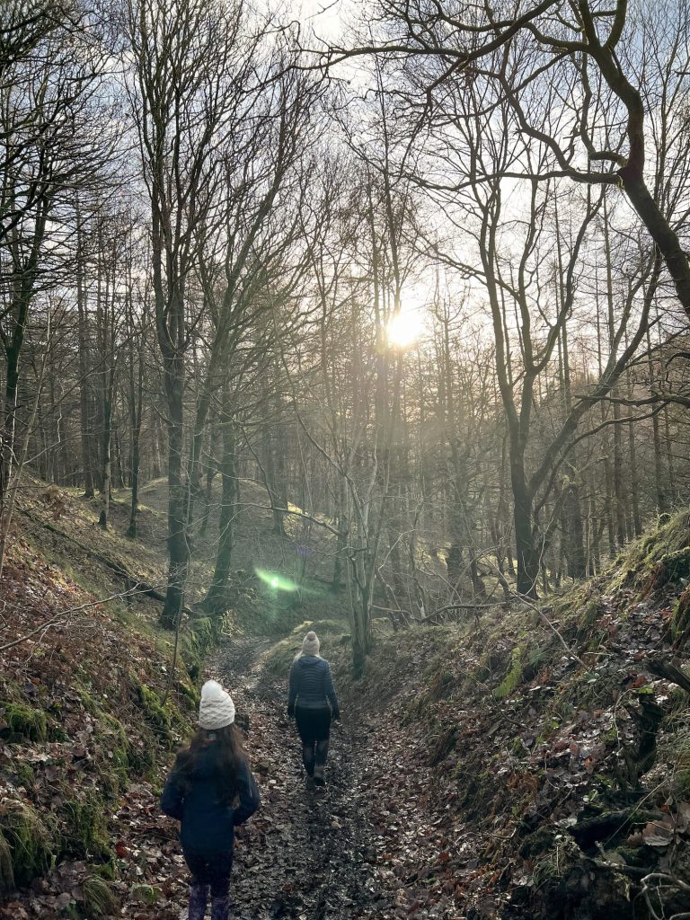 A woman and her daughter walking through the woods