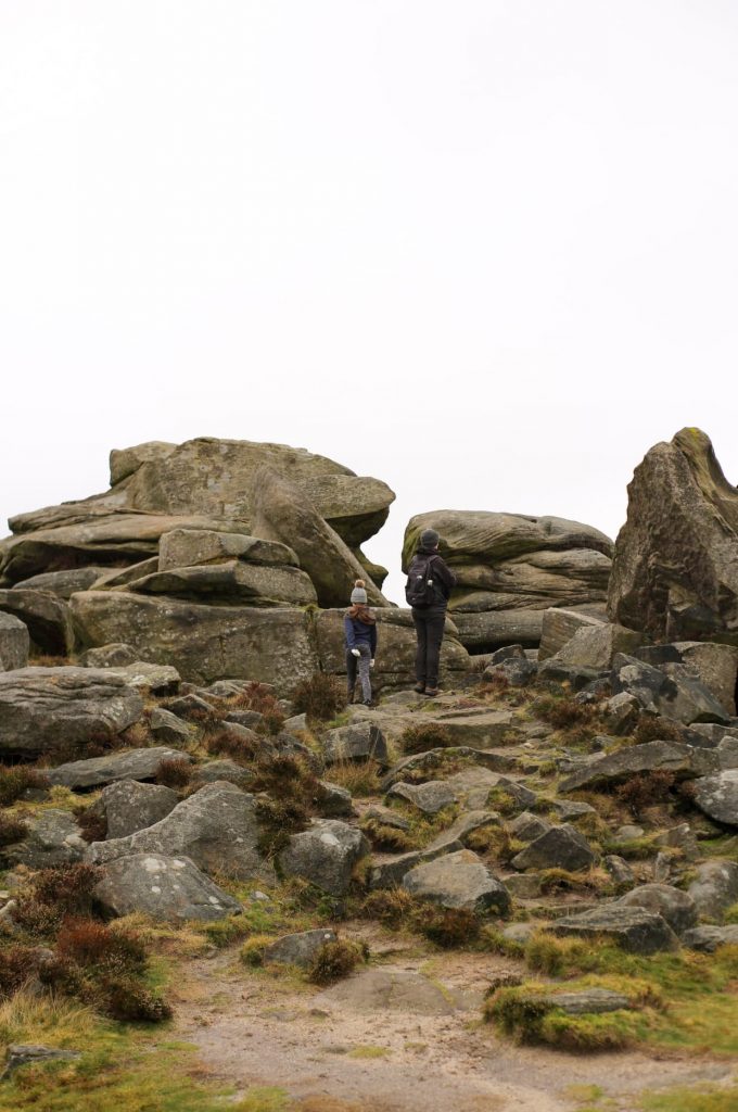A man and his daughter exploring a rock formation at Over Owler Tor