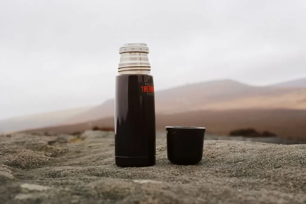 A black Thermos flask with a mountain background