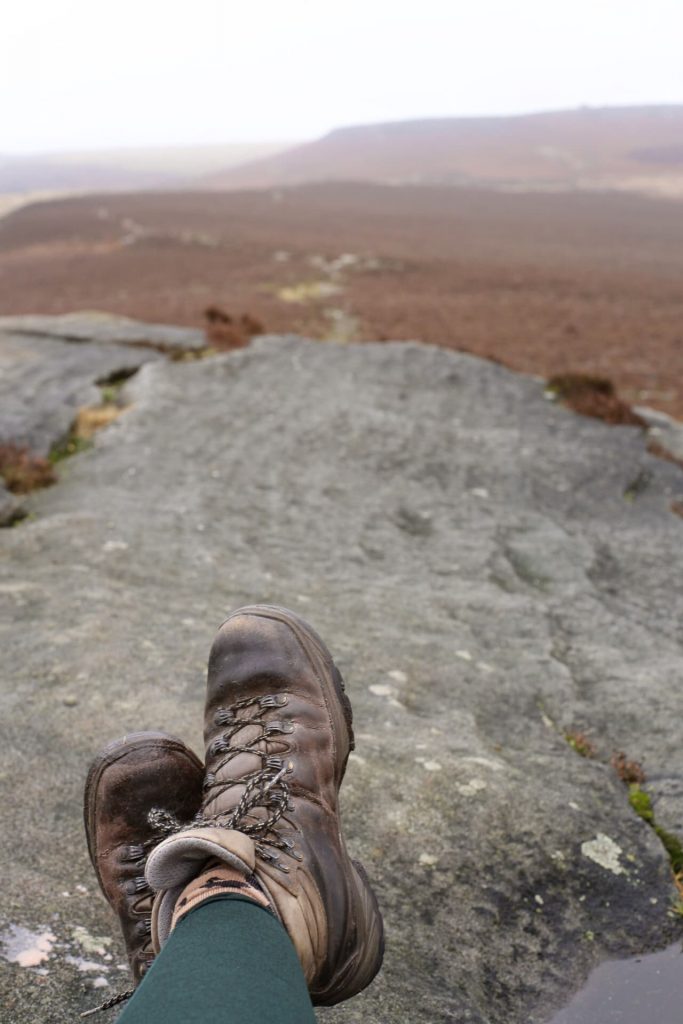 A pair of Scarpa hiking boots with a view to Higger Tor, Peak District