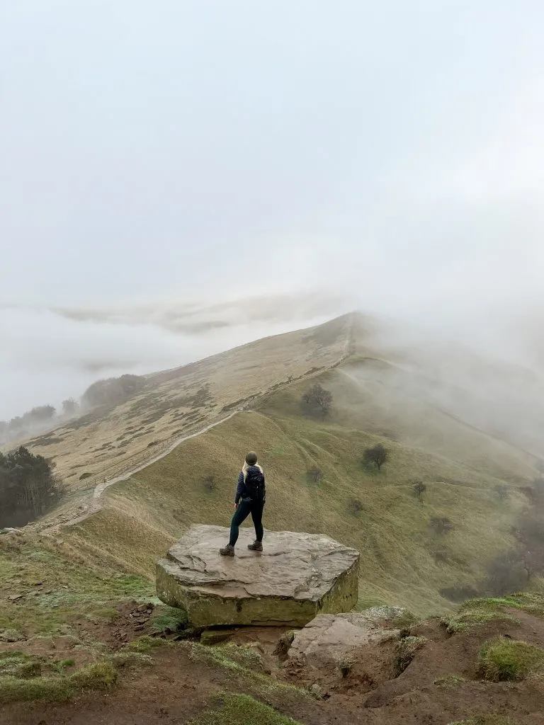 A woman standing on a rock on Back Tor looking along The Great Ridge