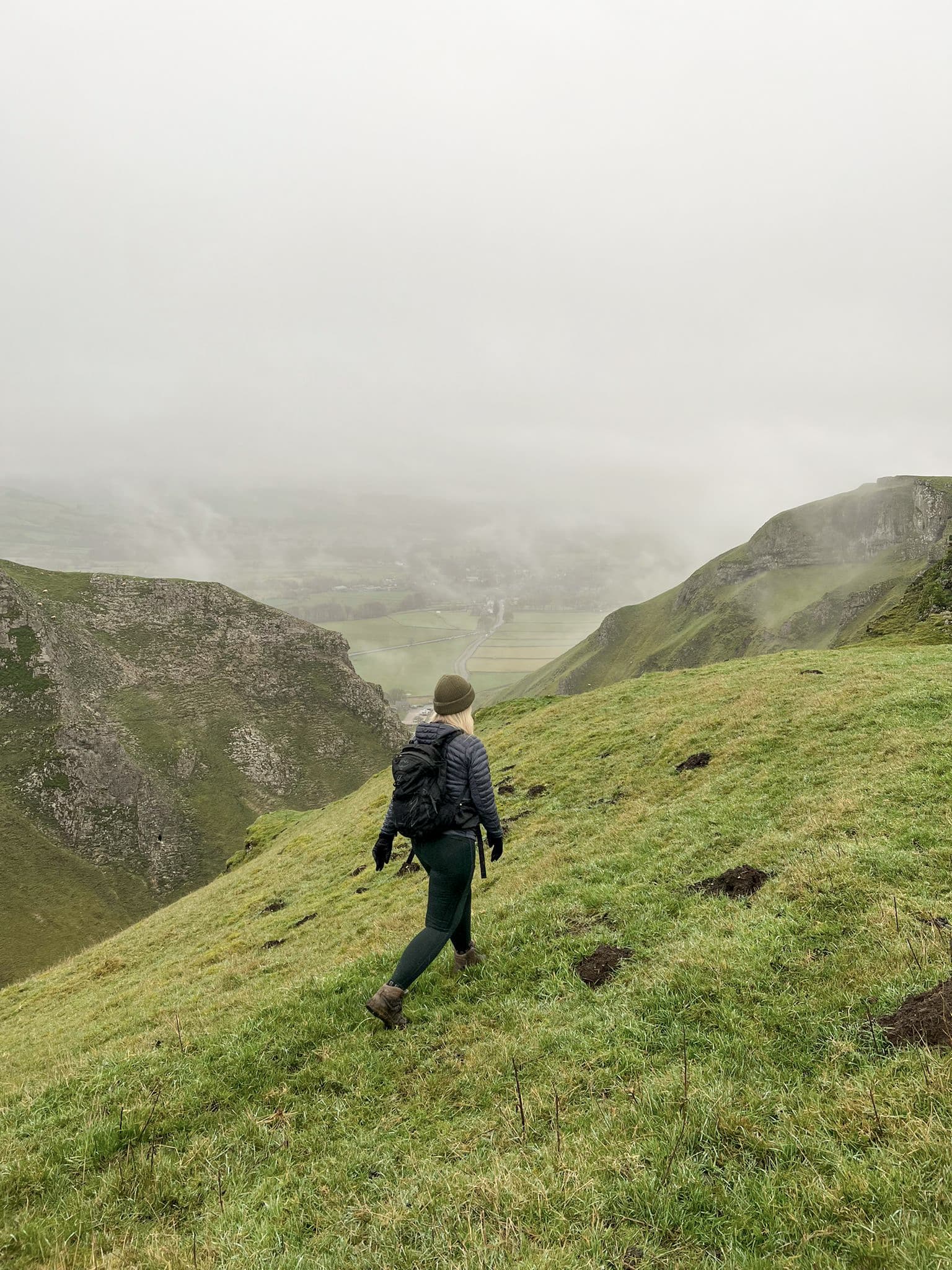 A woman walking along the top of Winnats Pass with a mist in the background