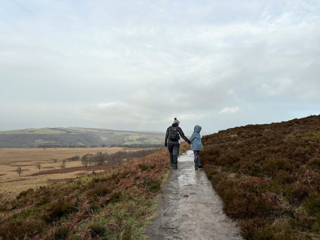 A father and daughter walking along White Edge in the Peak District
