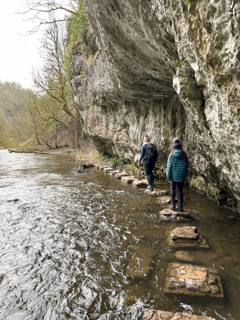 A woman and her daughter walking over some stepping stones 