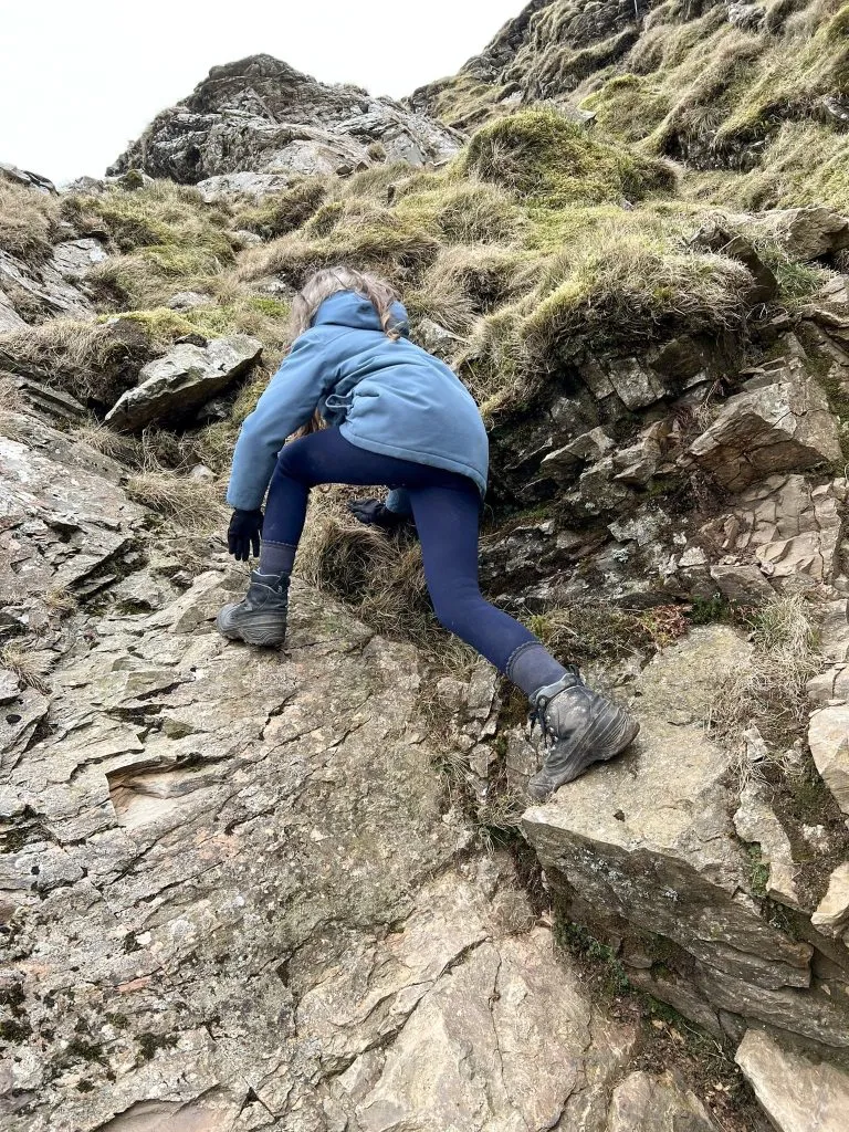 A young girl scrambling up Eel Crag