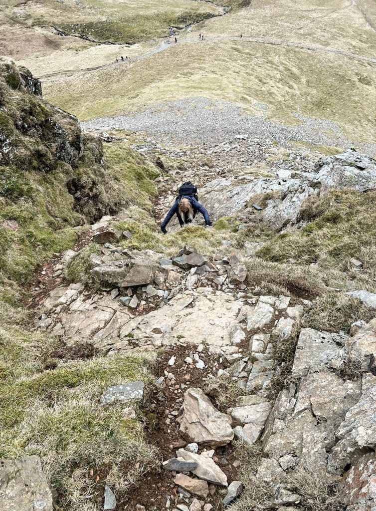 A woman scrambling up Eel Crag