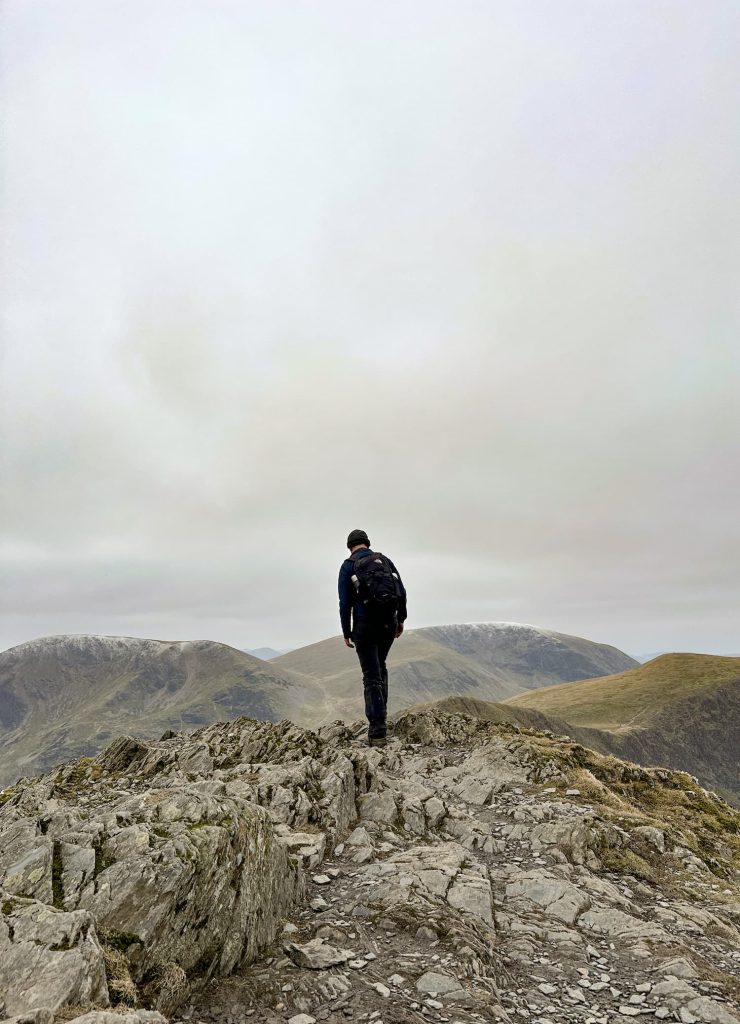 A man standing on the summit of Grisedale Pike