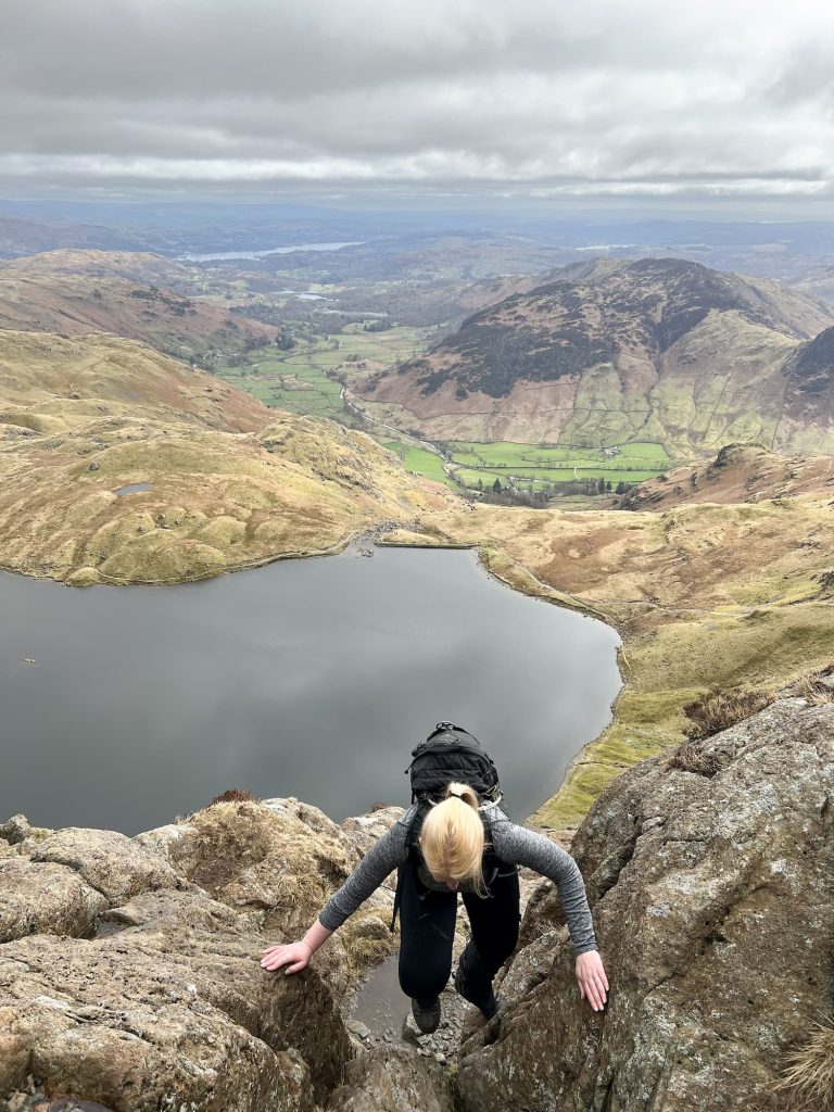 A blonde haired woman climbing a mountain in the Lake District
