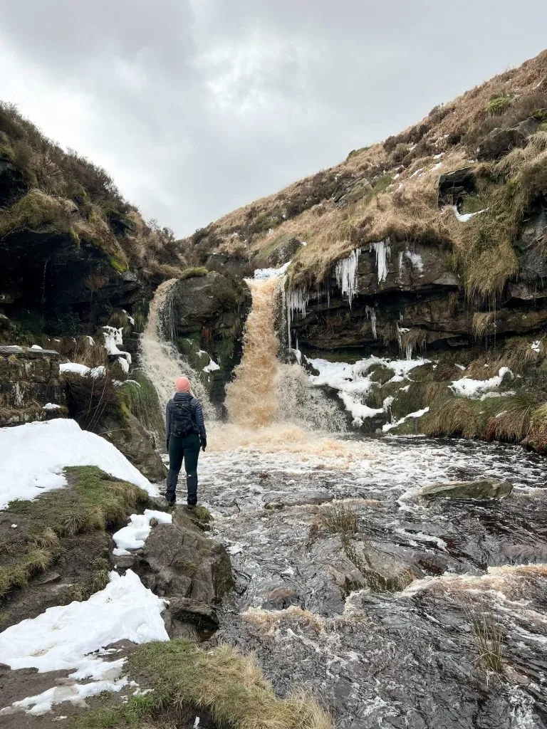 A woman looking up at a waterfall