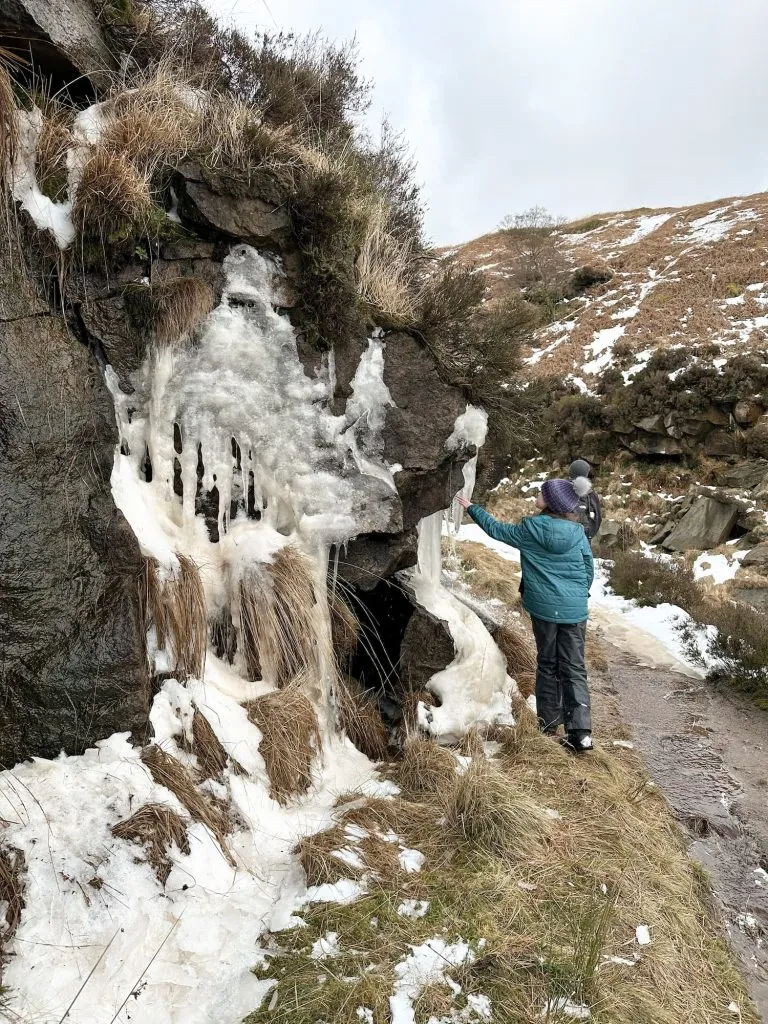 A young girl looking up at some large icicles