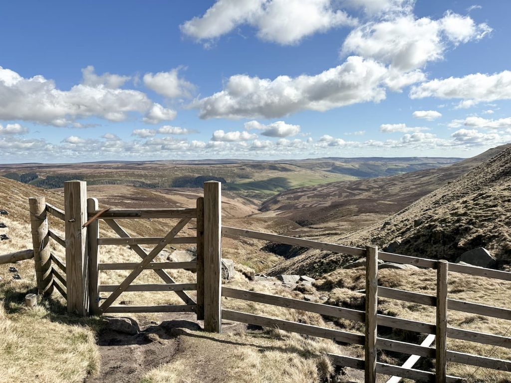 A wooden gate with a sunny moorland view beyond