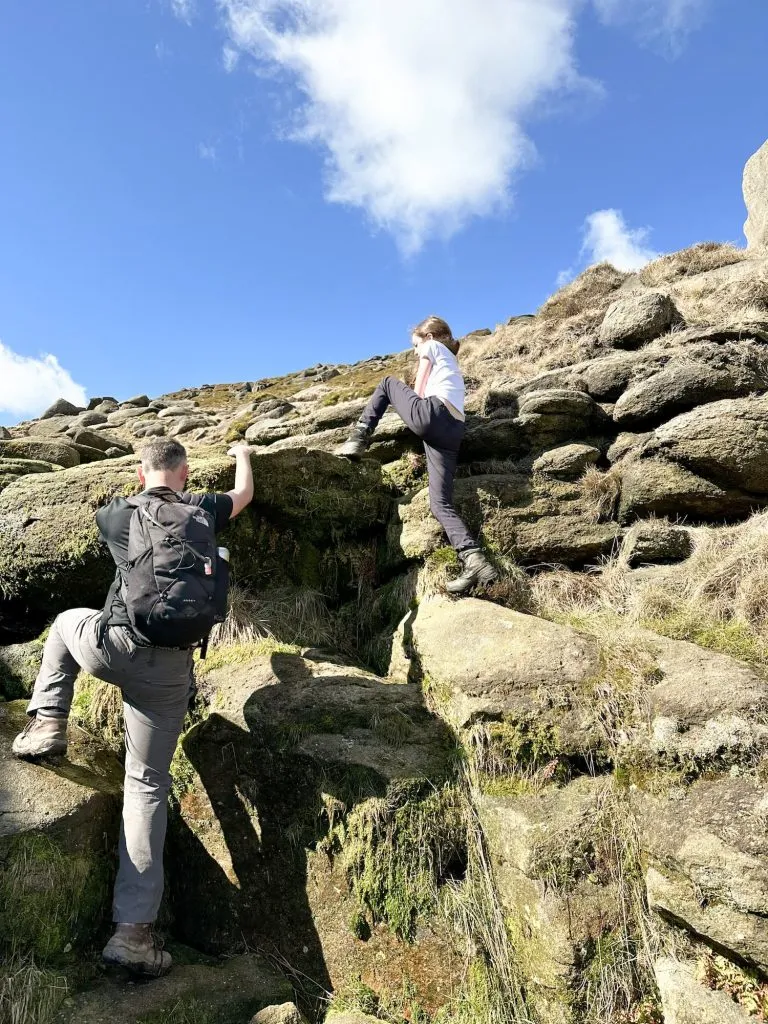A father and daughter climbing up some rocks
