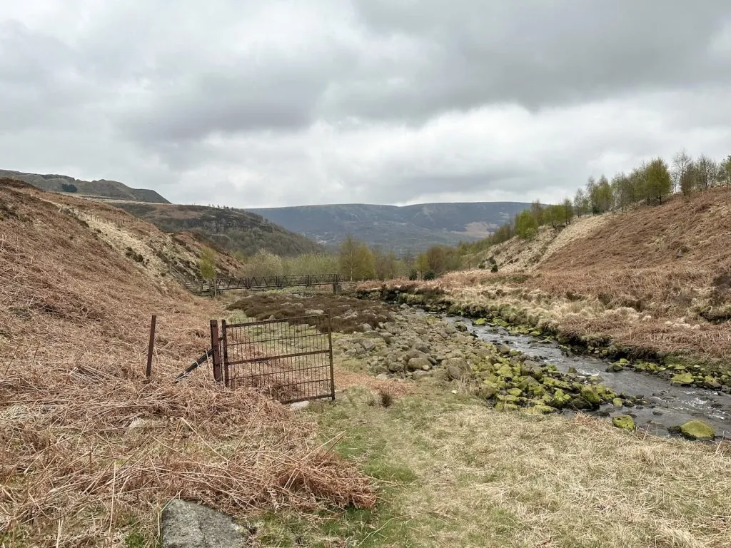 An old metal gate next to a stream