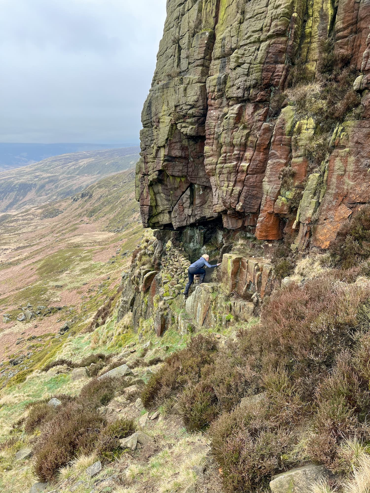 A woman climbing into a cave at Laddow Rocks