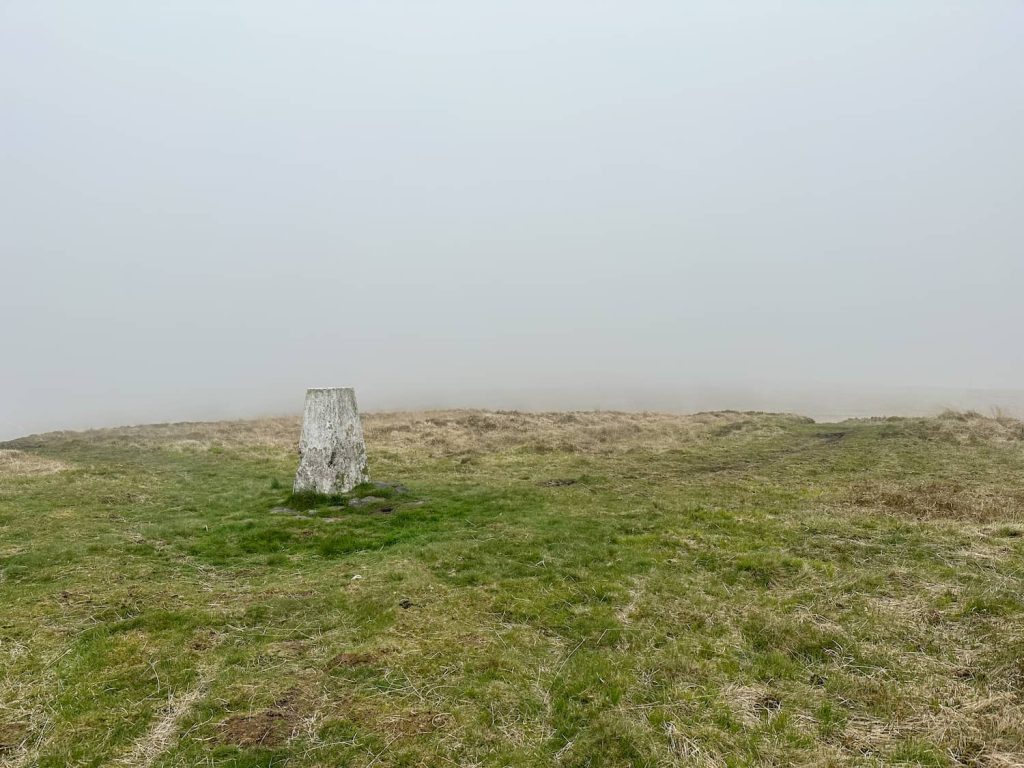 A misty view of Dog Hill trig point, a grey concrete pillar