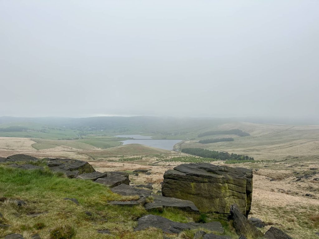 A misty murky view from a rocky outcrop over a reservoir.