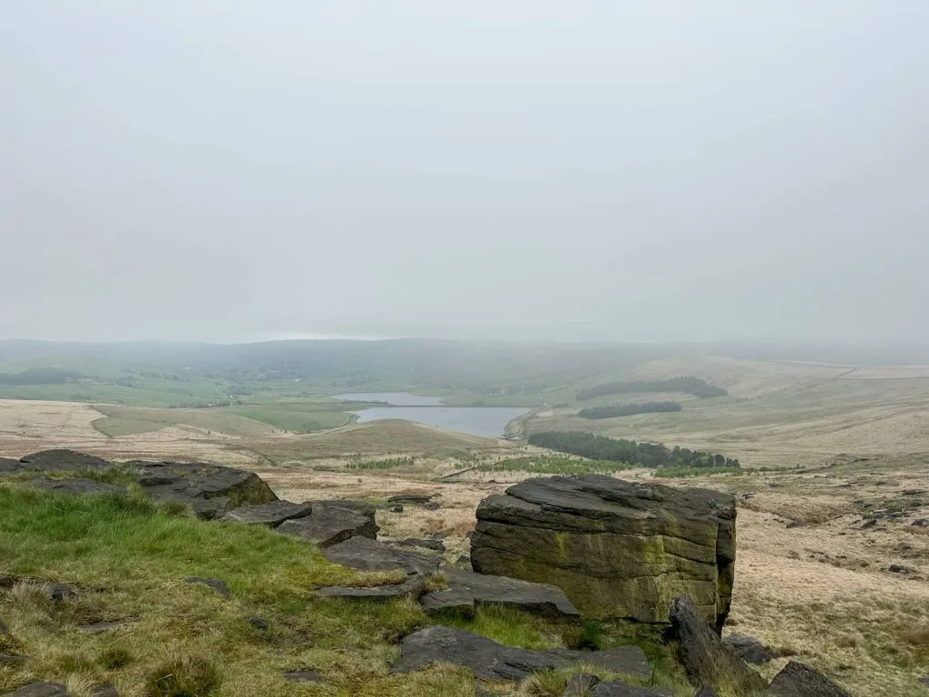 A misty murky view from a rocky outcrop over a reservoir.