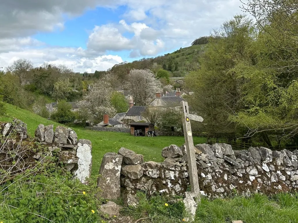 A wooden sign post and a dry stone wall